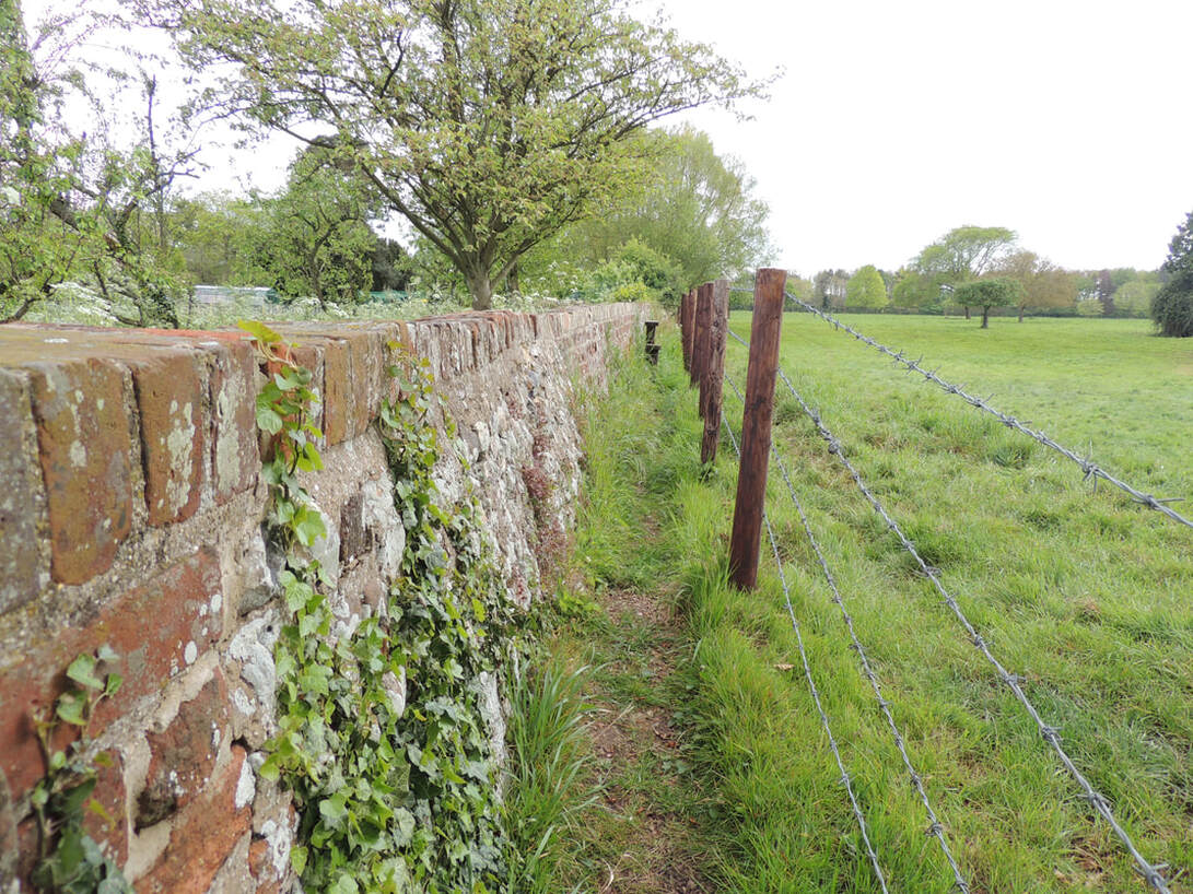 brick wall & barbed wire by field
